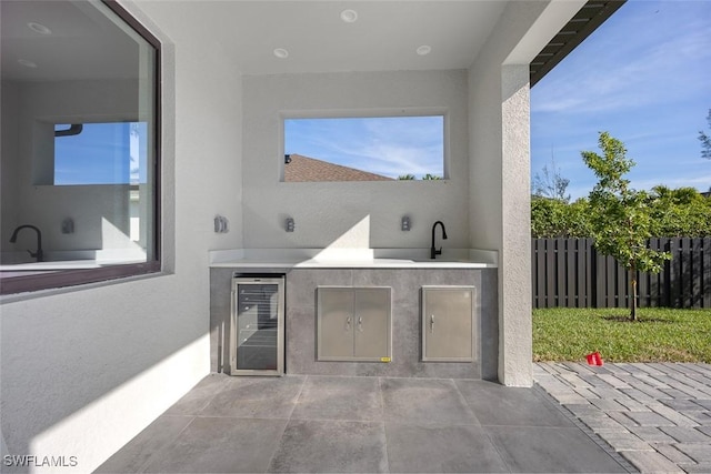 view of patio with wine cooler, a sink, fence, and area for grilling