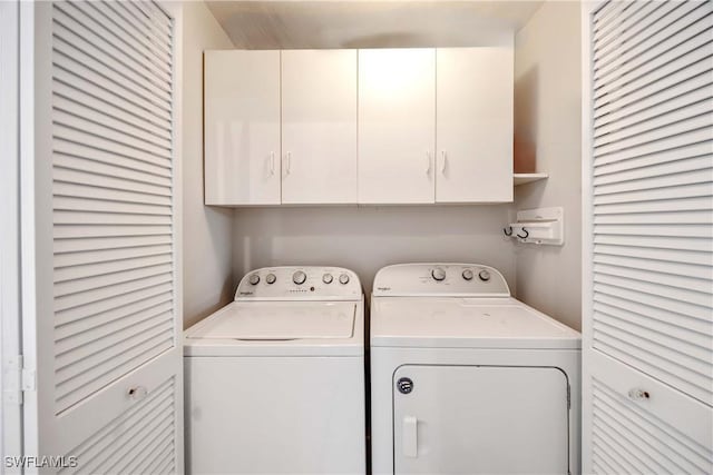 clothes washing area featuring cabinets and separate washer and dryer