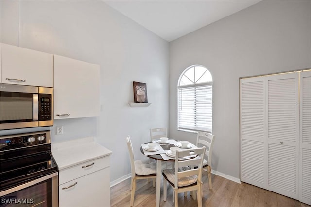 dining area with lofted ceiling and light wood-type flooring