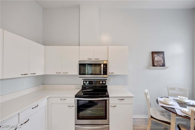 kitchen with white cabinets, light wood-type flooring, and appliances with stainless steel finishes