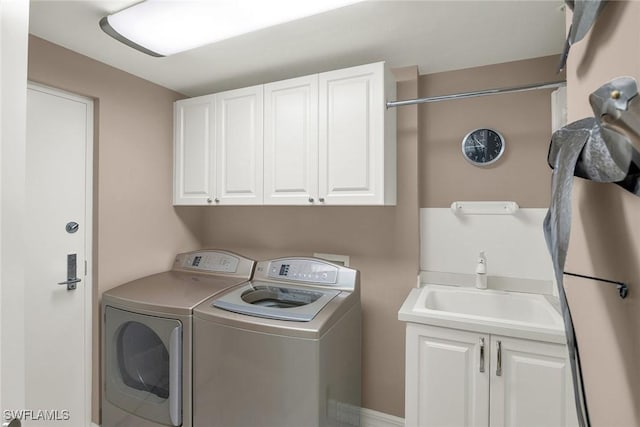 laundry area featuring cabinets, separate washer and dryer, and sink