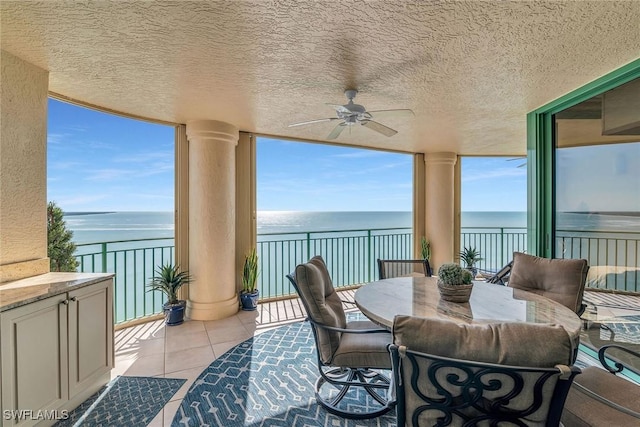 sunroom / solarium with ceiling fan and a water view