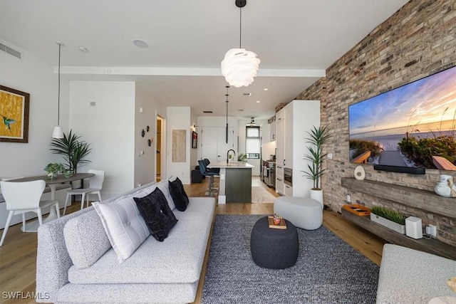 living room with hardwood / wood-style flooring, beam ceiling, and sink