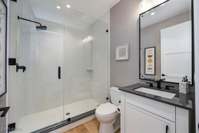 bathroom with wood-type flooring, vanity, toilet, and a shower with door