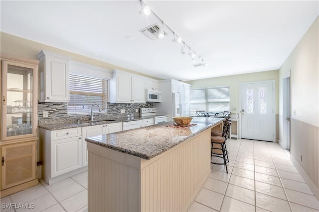 kitchen featuring white cabinets, sink, a kitchen island, and white appliances