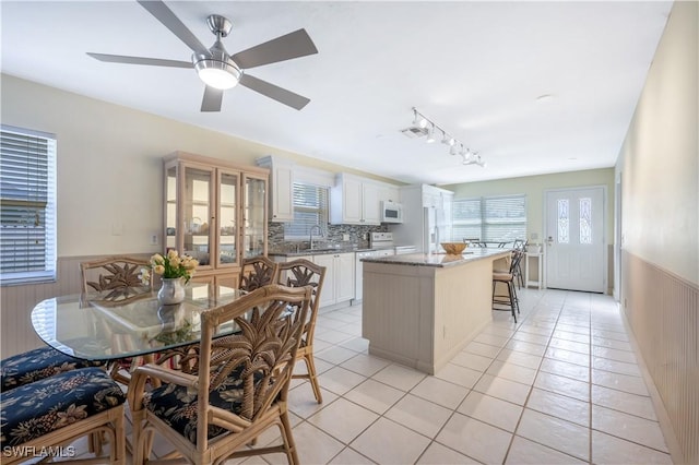 kitchen with sink, rail lighting, a kitchen island, white appliances, and white cabinets