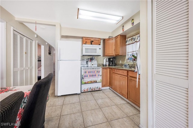 kitchen with decorative backsplash, white appliances, light stone counters, and sink