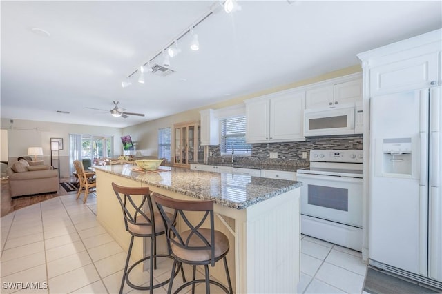 kitchen featuring a center island, white appliances, a breakfast bar area, and white cabinetry