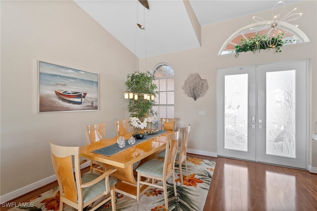 dining area with french doors, high vaulted ceiling, and hardwood / wood-style flooring