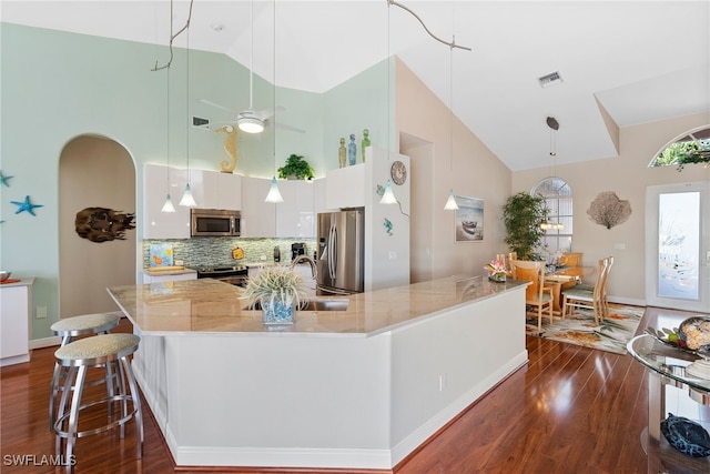 kitchen featuring decorative backsplash, appliances with stainless steel finishes, ceiling fan, high vaulted ceiling, and white cabinets