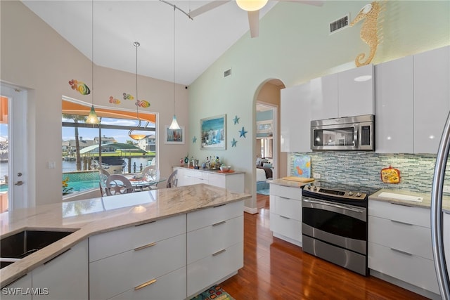 kitchen with appliances with stainless steel finishes, tasteful backsplash, a water view, white cabinets, and hanging light fixtures