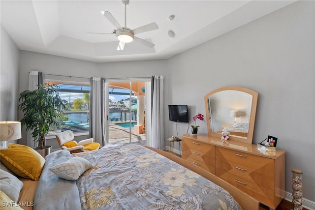 bedroom with a tray ceiling, access to exterior, and ceiling fan