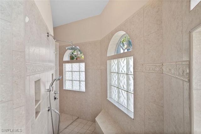 bathroom with a tile shower, tile patterned floors, and tile walls