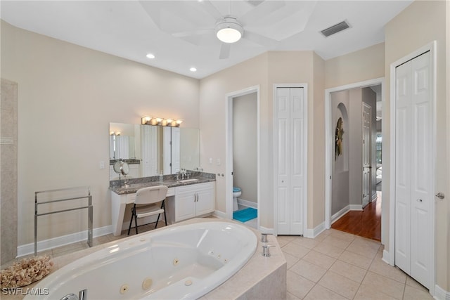 bathroom with vanity, tile patterned floors, a relaxing tiled tub, ceiling fan, and toilet