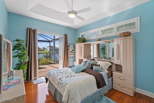 bedroom with access to exterior, ceiling fan, a water view, and light wood-type flooring