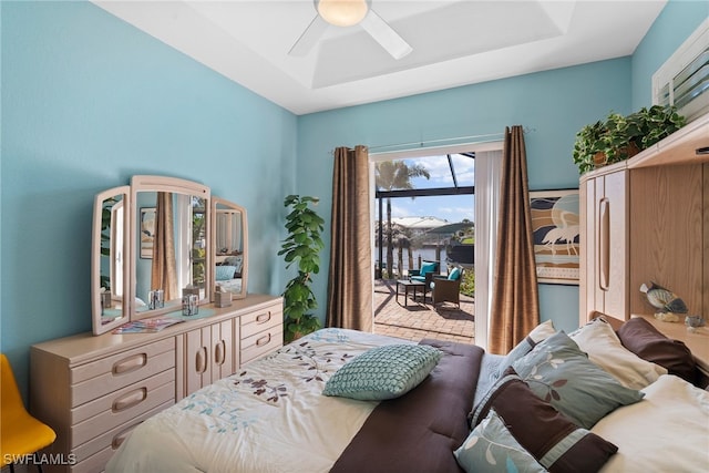 bedroom with access to outside, ceiling fan, and a tray ceiling