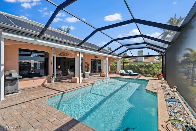 view of swimming pool with ceiling fan, glass enclosure, a patio, and grilling area