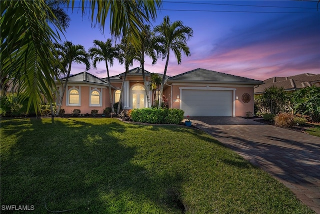 single story home featuring a garage and a lawn