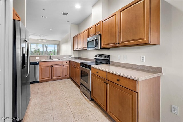 kitchen featuring appliances with stainless steel finishes, light tile patterned floors, ceiling fan, and sink