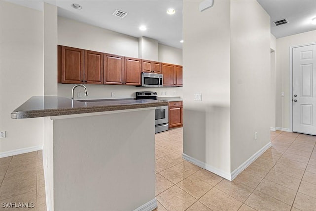 kitchen with kitchen peninsula, sink, light tile patterned flooring, and appliances with stainless steel finishes