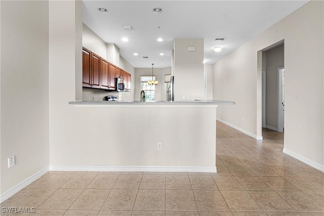 kitchen featuring pendant lighting, kitchen peninsula, stainless steel appliances, and light tile patterned floors