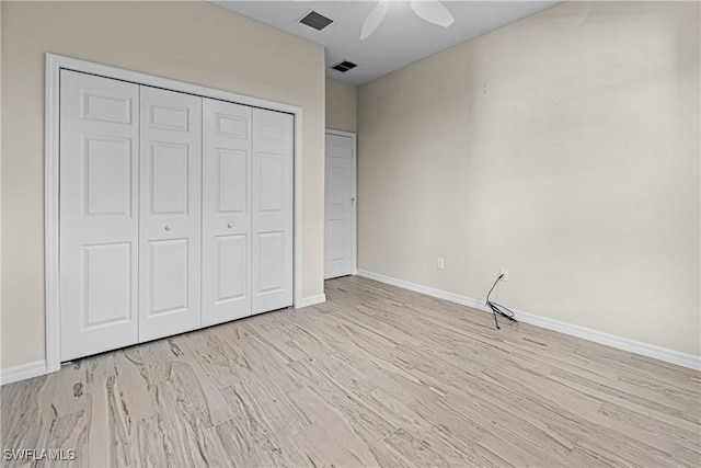 unfurnished bedroom with ceiling fan, a closet, and light wood-type flooring