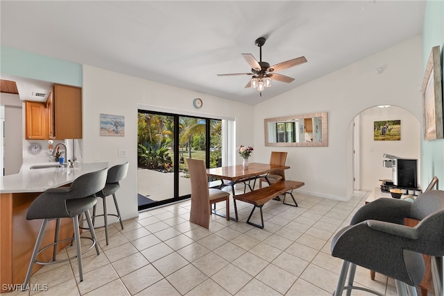 dining space featuring ceiling fan, sink, light tile patterned flooring, and vaulted ceiling