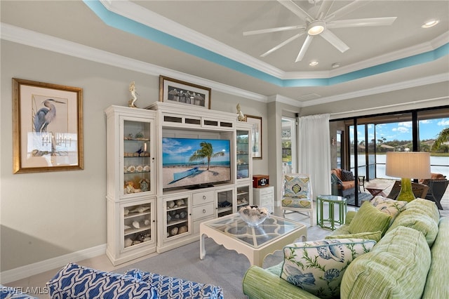 living room featuring a raised ceiling, crown molding, and ceiling fan