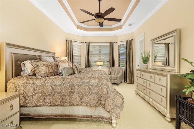 carpeted bedroom with a tray ceiling, ceiling fan, and crown molding