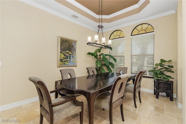 dining space with a chandelier, a tray ceiling, and ornamental molding