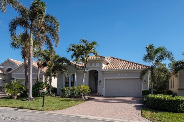 mediterranean / spanish-style home with a garage and a front lawn