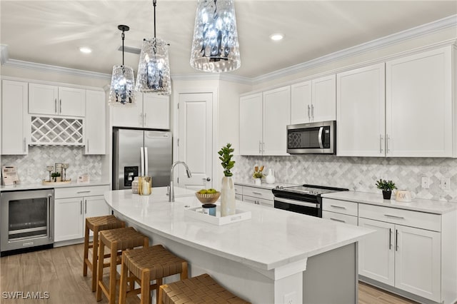 kitchen featuring wine cooler, white cabinets, an island with sink, and appliances with stainless steel finishes