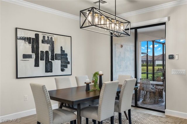 dining room with light hardwood / wood-style floors, ornamental molding, and a notable chandelier