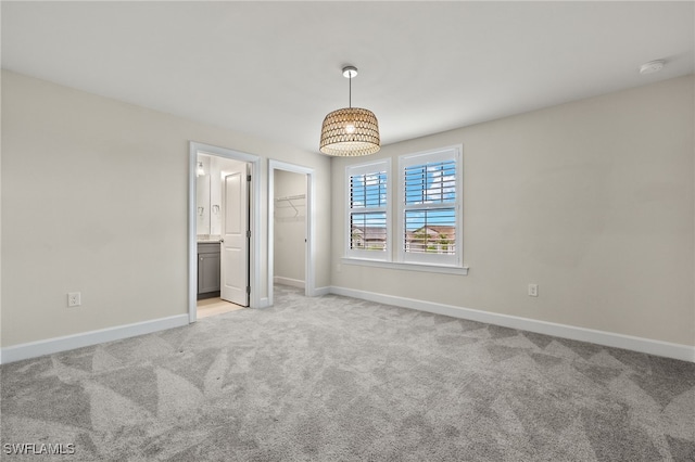 unfurnished bedroom featuring a spacious closet, a closet, and light carpet