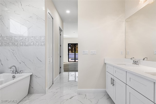 bathroom featuring baseboards, a freestanding bath, double vanity, marble finish floor, and a sink