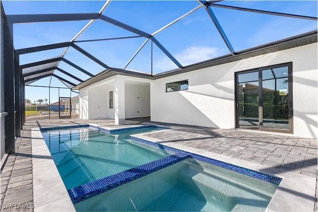 view of swimming pool with a patio area, glass enclosure, and a pool with connected hot tub