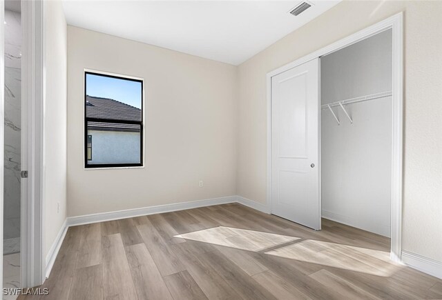 unfurnished bedroom featuring light wood finished floors, a closet, visible vents, and baseboards