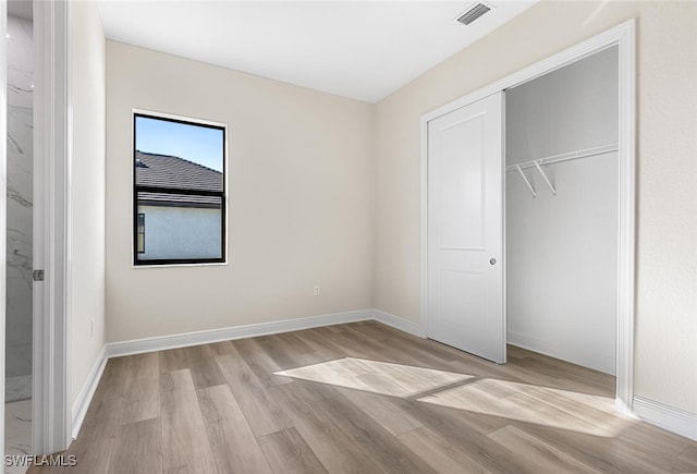 unfurnished bedroom with light wood-style flooring, baseboards, visible vents, and a closet