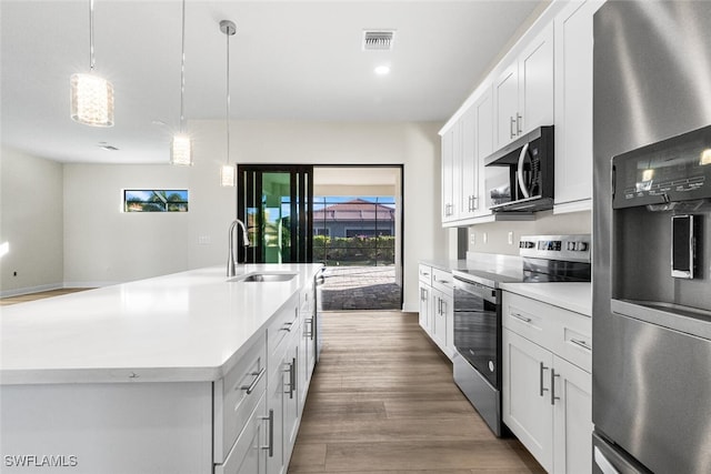 kitchen featuring visible vents, a sink, wood finished floors, appliances with stainless steel finishes, and light countertops