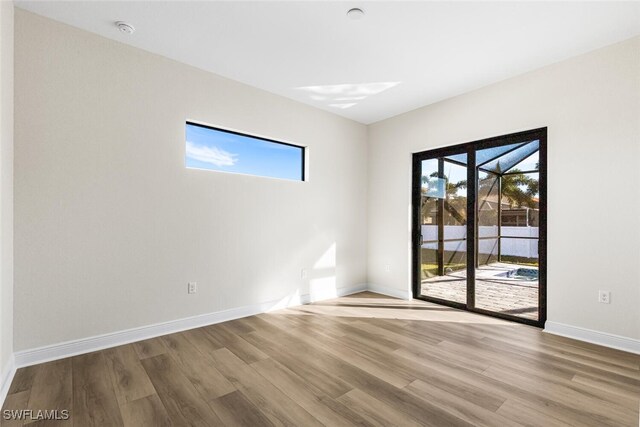 empty room featuring baseboards, light wood-style flooring, and a healthy amount of sunlight