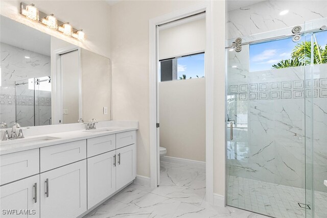 bathroom featuring marble finish floor, a healthy amount of sunlight, a sink, and a marble finish shower