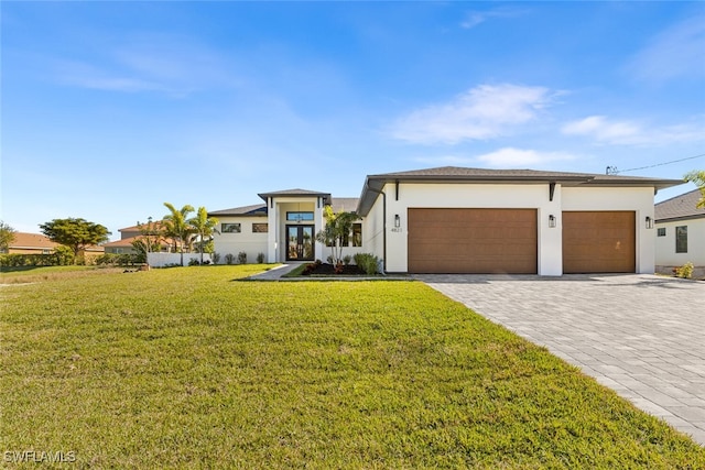 prairie-style house featuring a front lawn, stucco siding, french doors, decorative driveway, and an attached garage