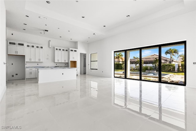 kitchen featuring a healthy amount of sunlight, white cabinetry, a kitchen island, and light stone counters