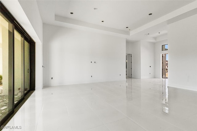 spare room with light tile patterned floors, a towering ceiling, and a raised ceiling