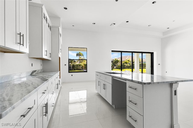 kitchen featuring light stone countertops, a center island, white cabinets, and plenty of natural light