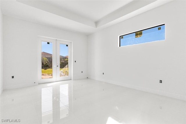 unfurnished room with french doors, a raised ceiling, and light tile patterned flooring