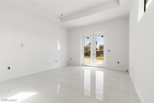 empty room with french doors and a raised ceiling