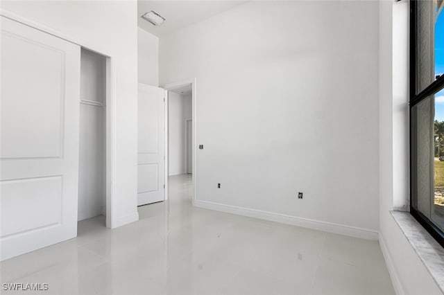 unfurnished bedroom featuring light tile patterned floors, a closet, and multiple windows