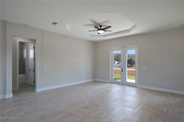 empty room featuring a tray ceiling, baseboards, visible vents, and french doors