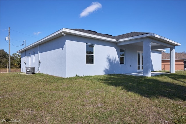 view of side of property with french doors, a lawn, central AC, and stucco siding